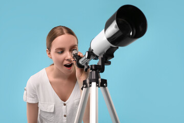 Emotional astronomer looking at stars through telescope on light blue background