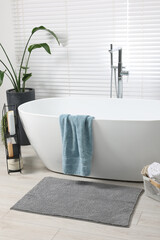 Stylish bathroom interior with bath tub, houseplant and soft light grey mat - obrazy, fototapety, plakaty