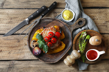 Delicious grilled meat and vegetables served with sauces on wooden table, flat lay