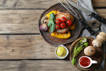 Delicious grilled meat and vegetables served with sauces on wooden table, flat lay. Space for text