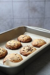 Baking pan with chocolate chip cookies on table, closeup. Space for text