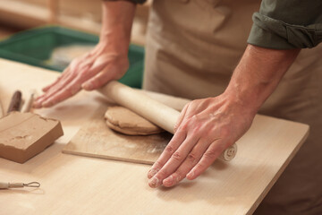 Obraz na płótnie Canvas Man crafting with clay at table indoors, closeup