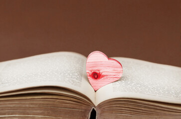 Ein rotes Herz aus Holz auf einem alten Buch