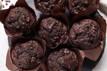 Tasty chocolate muffins on light table, top view
