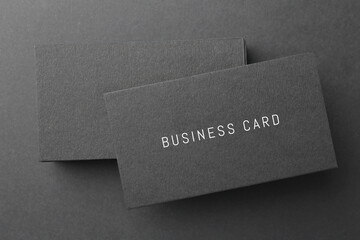 Stack of business cards on black background, top view