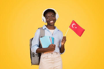 Smiling teen african american woman student in wireless headphones, with books, flag of China