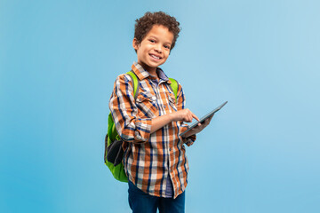 Smiling student with tablet and backpack, blue backdrop