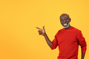 Happy senior Black man with a white beard, pointing to the side with a big smile