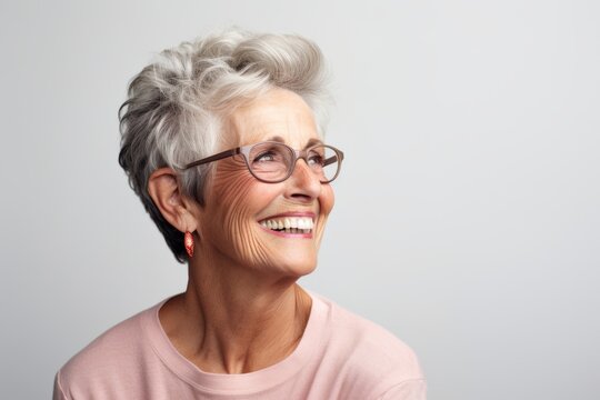 Portrait of a happy senior woman with eyeglasses over grey background