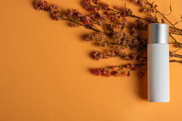 Cosmetic product in tube, bottle, lotion or serum and dried flowers on cream background. 