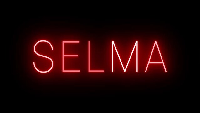 Flickering red retro style neon sign glowing against a black background for SELMA
