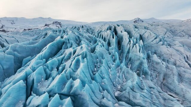 Aerial landscape view over textured ice formations of a glacier in Iceland, at dusk