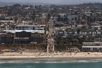 Fototapeta premium Oceanside community on a beach in California. Bustling and thriving tourist destination where you can shop, eat, and entertain. Sand and palm trees guide the way into the lax life of the west coast