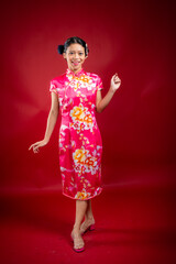 Portrait of an attractive Asian Chinese female wearing cheongsam or qipao on red background for Chinese New Year concept