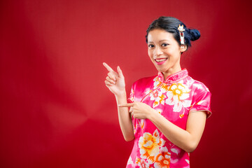 Portrait of an attractive Asian Chinese female wearing cheongsam or qipao on red background for Chinese New Year concept