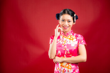 Portrait of an attractive Asian Chinese female wearing cheongsam or qipao on red background for Chinese New Year concept