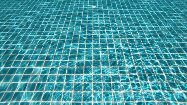 underwater view of outdoor swimming pool, the sun's ray pass through the water slow motion scene