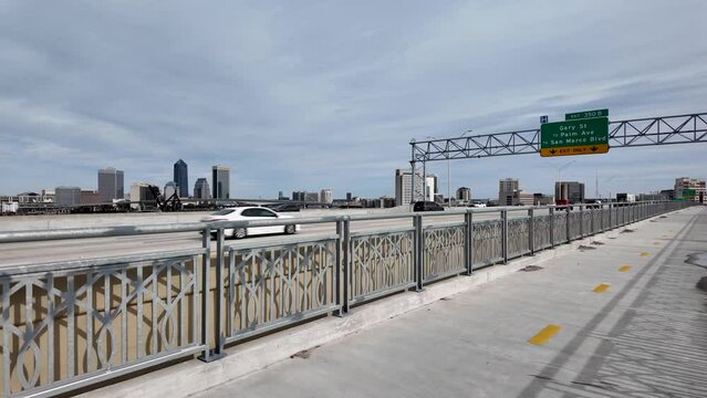 Traffic passing by on the Fuller Warren Bridge with downtown Jacksonville in the background.