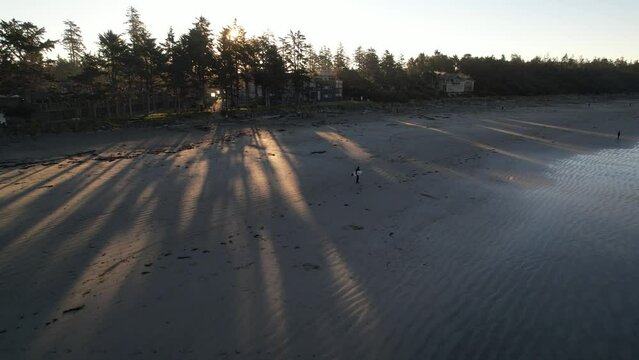 Surfer walking down a beach in Tofino, Canada