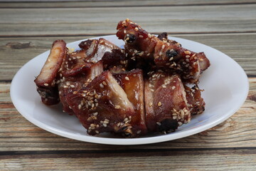 Traditional roasted or grilled marinated pork rib dressing with white sesame serving on the plate. Famous appetizer menu in party.