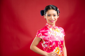 Portrait of an attractive Asian Chinese female wearing cheongsam or qipao on red background for Chinese New Year concept