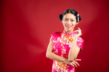 Portrait of an attractive Asian Chinese female wearing cheongsam or qipao on red background for Chinese New Year concept