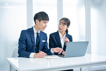 パソコンを見ながら話す2人のビジネスパーソン
