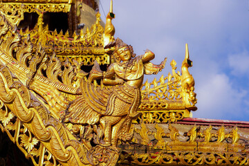 Fototapeta premium Closeup and crop antique golden carved wood Burmese art on the roof of the Burmese temple chapel in Lampang province, Thailand.