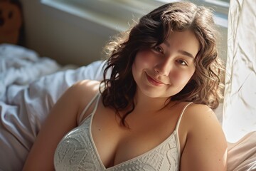 A plump beautiful woman, 25 years old, relaxes and smiles at the camera in her bedroom.