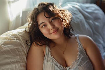 A plump beautiful woman, 25 years old, relaxes and smiles at the camera in her bedroom.