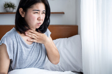 unwell Asian woman suffering from nausea in bed. food poisoning or pregnancy concept