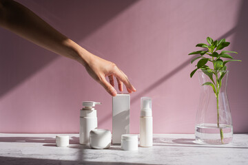 Hand is touching skincare set for cosmetic and beauty concept. - obrazy, fototapety, plakaty