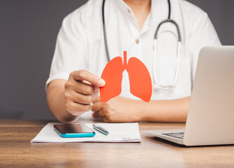 Doctor holding a lung-shaped symbol while sitting at a desk in the hospital.