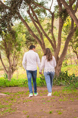 Fototapeta premium Family members holding hands and walking backwards in a park together family