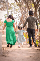 Fototapeta premium Family members holding hands and walking backwards in a park together family