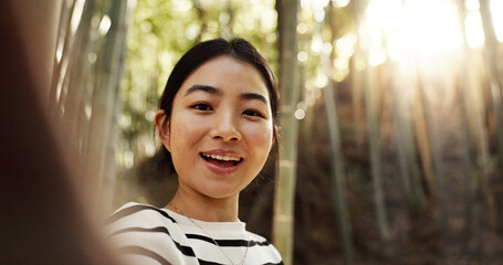 Japanese woman, selfie and bamboo forest for portrait with smile, pride and bush for post on web blog. Girl, person and happy influencer on adventure, trekking and hiking by trees for social network