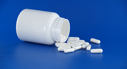 Medicine bottle spills white pills over blue surface