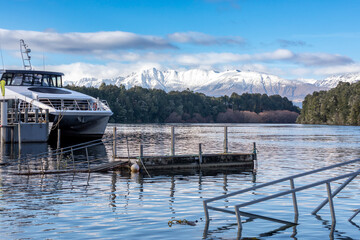 Photograph of snow-capped mountains and flood waters in the Waiau River at the Manapouri Boat Club in Fiordland on the South Island of New Zealand