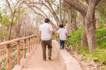 Fototapeta premium Family members holding hands and walking backwards in a park together family