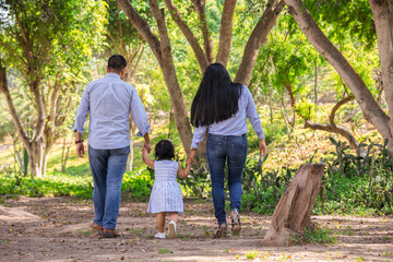 Family members holding hands and walking backwards in a park together family