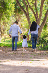 Naklejka na ściany i meble Family members holding hands and walking backwards in a park together family