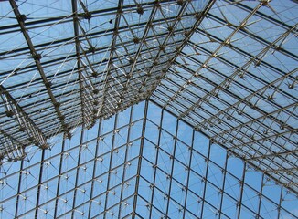 Inside view of the roof made of glass at Louvre Museum under the blue sky in summer in Paris, France