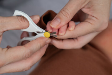 Mom cuts her newborn son's fingernails with small children's scissors.