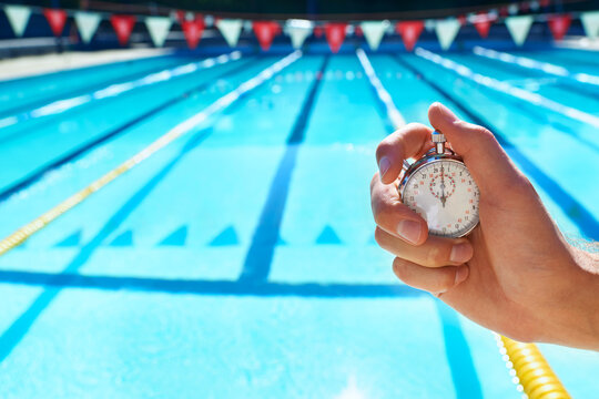 Hand, timer and swimming pool for sport, training and workout with preparation for competition. Person, coach or mentor with clock, stopwatch or check for speed, progress and tracking lap for race
