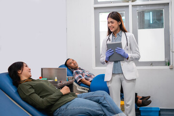 Uniformed female doctor carrying a tablet computer while chatting with a female patient lying down...