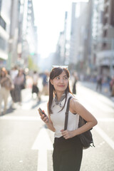 Tokyo tech stroll, Asian woman immersed in her smartphone, blending modern technology with urban lifestyle.