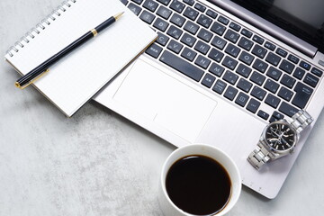 コーヒーを飲みながらノートパソコンでデスクワーク中のイメージ	
