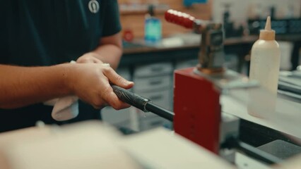 Vice grip holds down golf club shaft as caucasian male hands slide golf grip onto golf club shaft for custom fitting in workshop in slow motion
