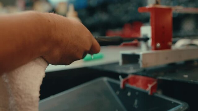 Caucasian male hands push and slide grip onto golf club shaft with water droplets dripping as vice holds club still for custom fitting in workshop in slow motion