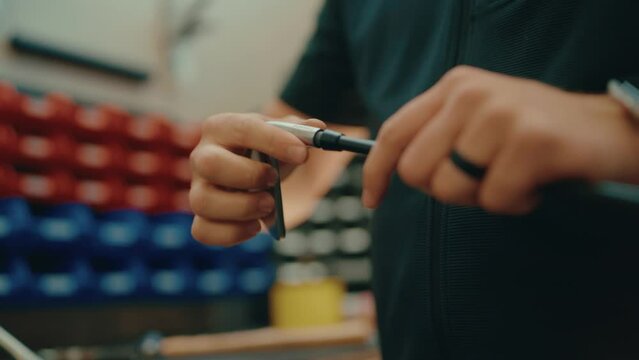 Golf club builder's hands twist iron head onto golf club shaft and secure for custom build in workshop in slow motion